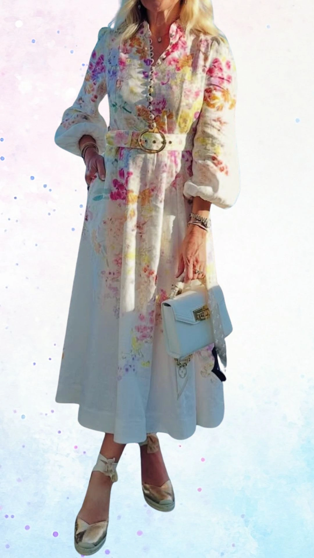 The outfit features a long, flowing white dress adorned with soft pink, yellow, and green floral patterns, crafted from lightweight fabric to enhance comfort. It includes a high collar, puffed sleeves, and a cinched waist accentuated by a wide belt with a circular buckle. Paired with metallic espadrille wedges, this graceful look is perfect for celebrating a baby shower.