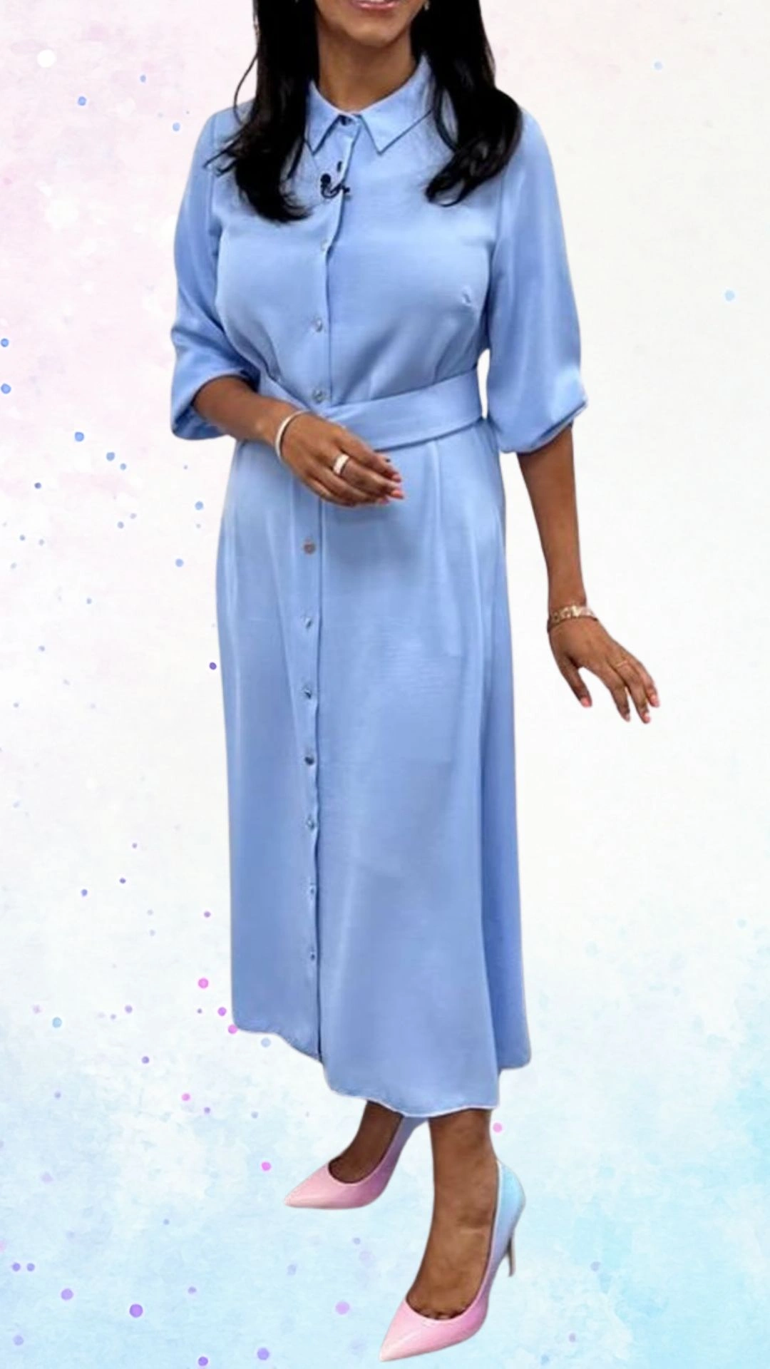 The outfit features a soft, pastel blue button-down dress made from a smooth fabric, with three-quarter sleeves and a belted waist that adds shape. The dress has a classic collar and a midi length, while the hem is slightly curved, providing an elegant silhouette. Complementing the ensemble are two-tone pink and blue heels, enhancing the celebratory feel appropriate for a baby shower.