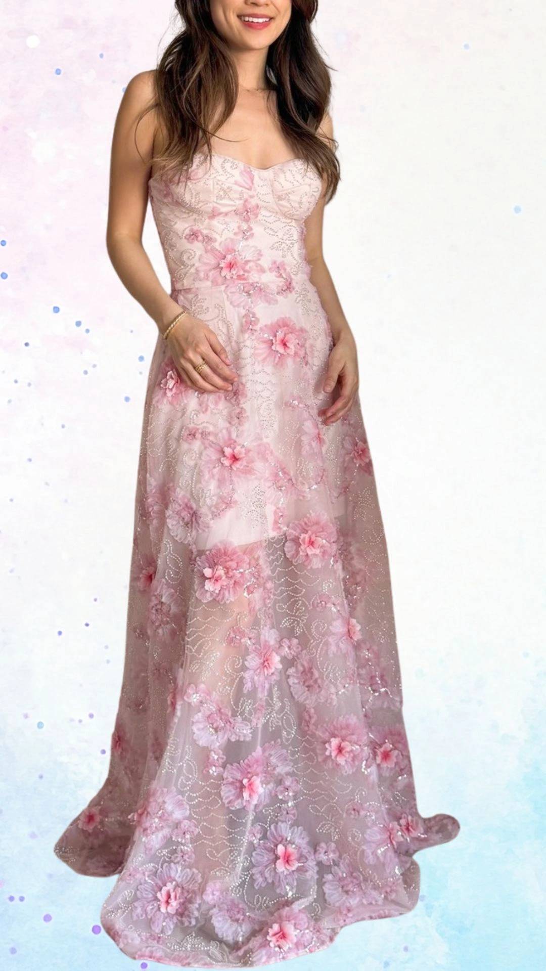 The outfit features a long, strapless gown in soft pink chiffon adorned with intricate floral appliqués and delicate beadwork, creating a whimsical yet elegant look. The flowing fabric drapes beautifully, while a subtle sweetheart neckline adds a touch of femininity, making it perfect for a baby shower celebration. The gown's gentle textures and embellishments evoke a sense of joy and celebration for the upcoming arrival.