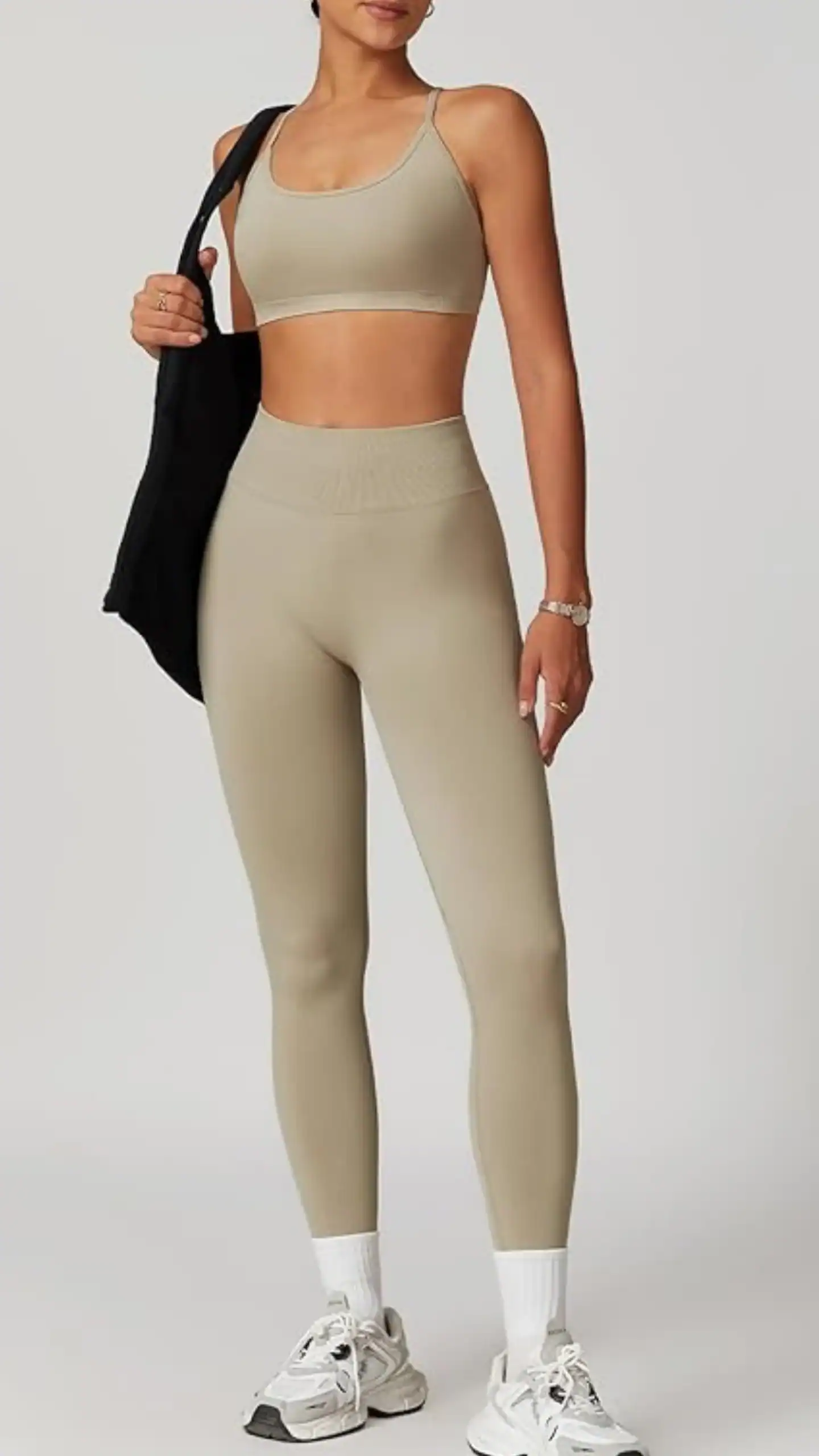 High-waisted, seamless, and form-fitting leggings paired with a matching strappy sports bra in a smooth beige hue, crafted from a stretchy blend of polyester and elastane for comfort and support. This contemporary workout set features a chic criss-cross back design and a sleek overall vibe, making it ideal for summer exercise sessions or casual outings.