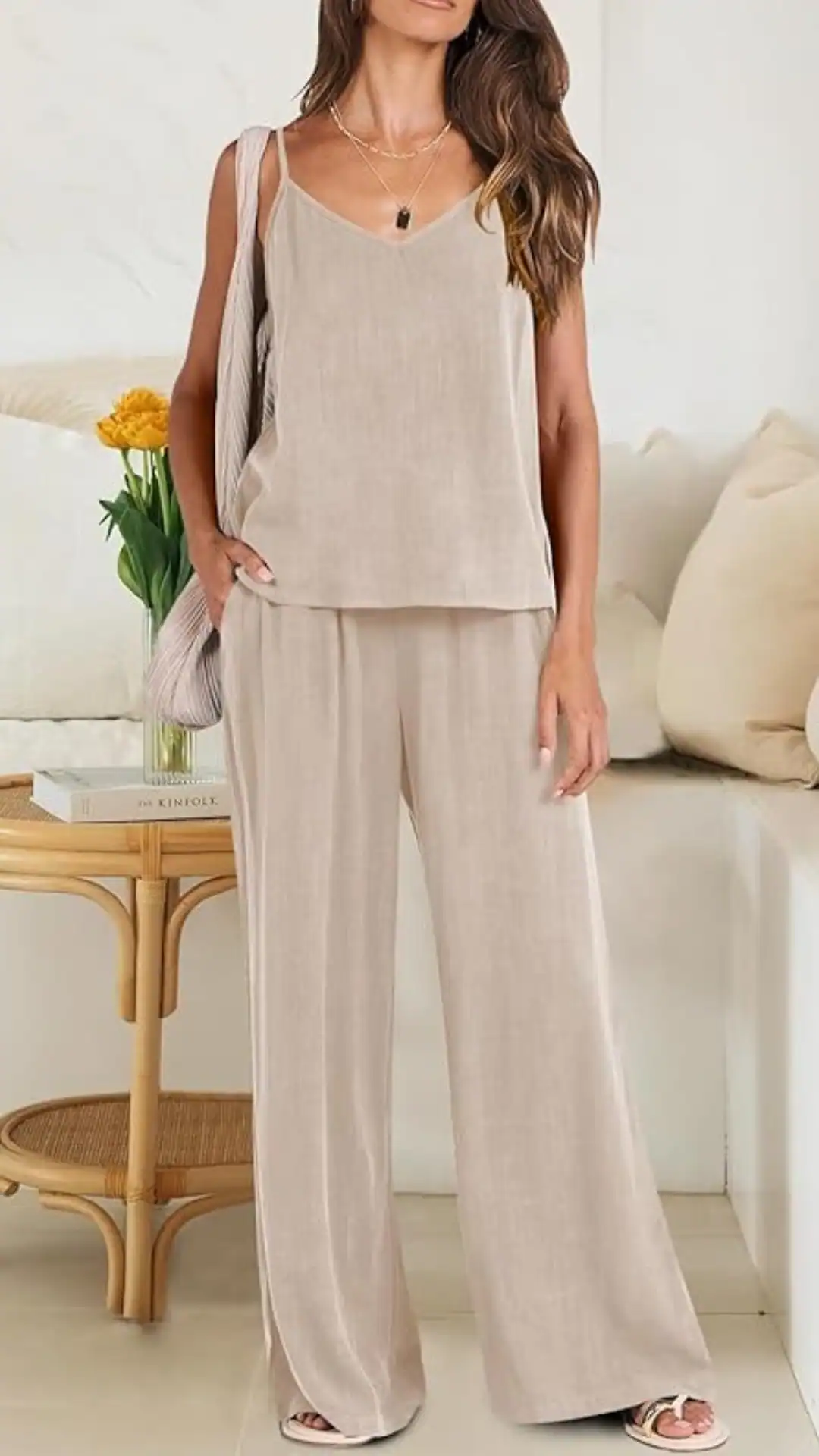 This outfit features a soft, light beige linen matching set with a relaxed fit, characterized by a sleeveless, v-neck top paired with wide-leg pants, creating a breezy and comfortable silhouette. Ideal for casual outings or warm-weather gatherings, the ensemble exudes a minimalist and effortlessly chic vibe, complemented by subtle textures that enhance its airy feel.