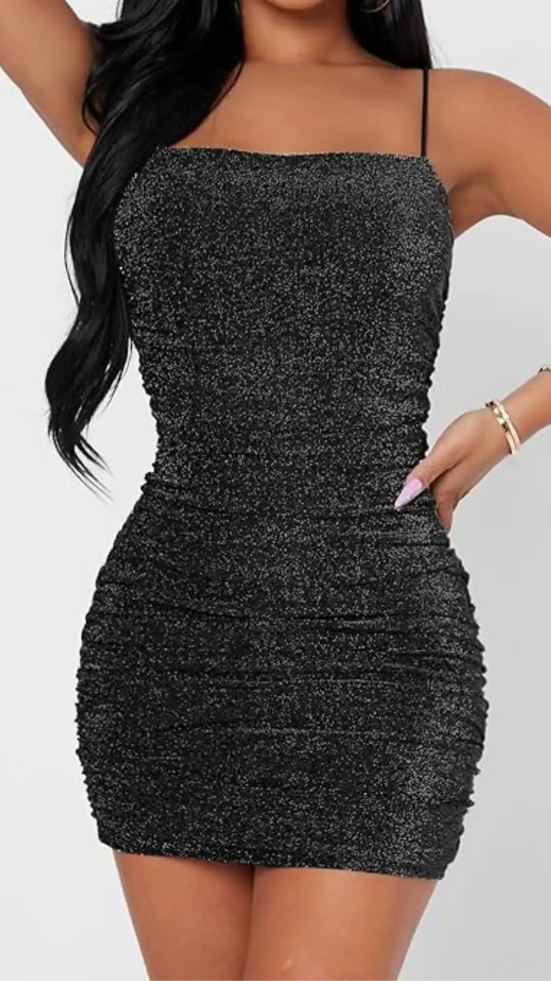 This black homecoming dress features a sleek, figure-hugging silhouette with a shimmering, textured fabric that catches the light elegantly. The design includes thin spaghetti straps, a ruched body, and a mini length, creating a bold and glamorous vibe ideal for a festive occasion like homecoming, perfect for teenage girls looking to make a stunning statement.
