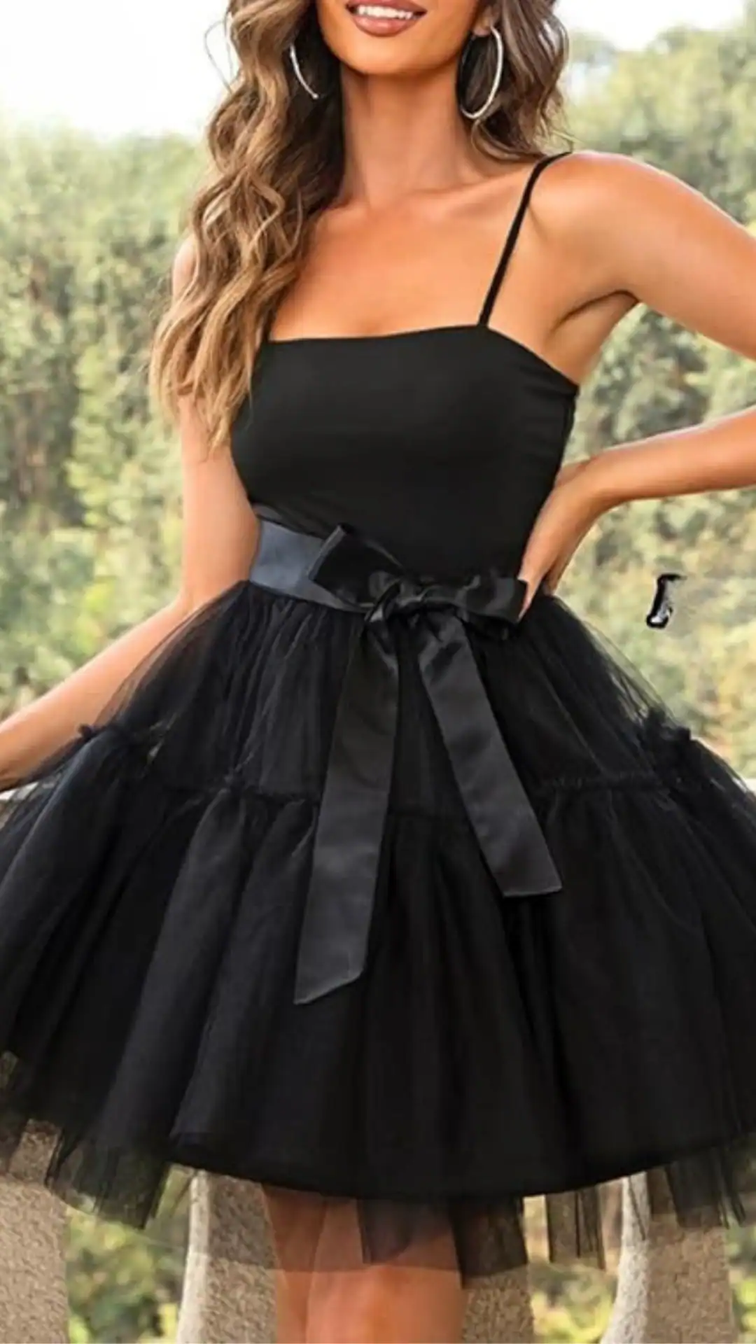 This stylish black homecoming dress features a fitted bodice with delicate spaghetti straps and a voluminous skirt made of soft tulle, creating a playful silhouette. The solid black color is enhanced by a satin bow at the waist, giving a cute yet elegant vibe, perfect for teen girls attending formal events like homecoming or school dances.
