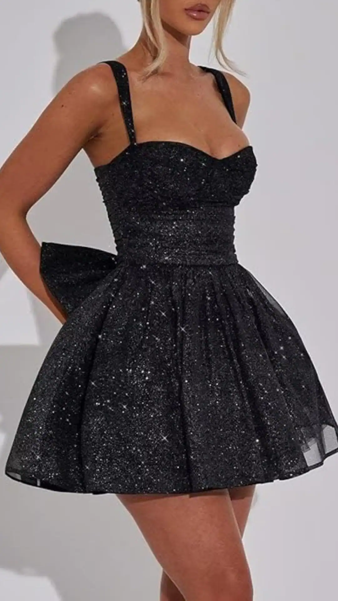 This black homecoming dress features a fitted bodice with a sweetheart neckline and playful, voluminous skirt, crafted from a textured fabric adorned with shimmering sequins, creating a starry effect. The design exudes a trendy vibe suitable for formal events, appealing to teenage girls looking for a bold, stylish option for homecoming or prom.