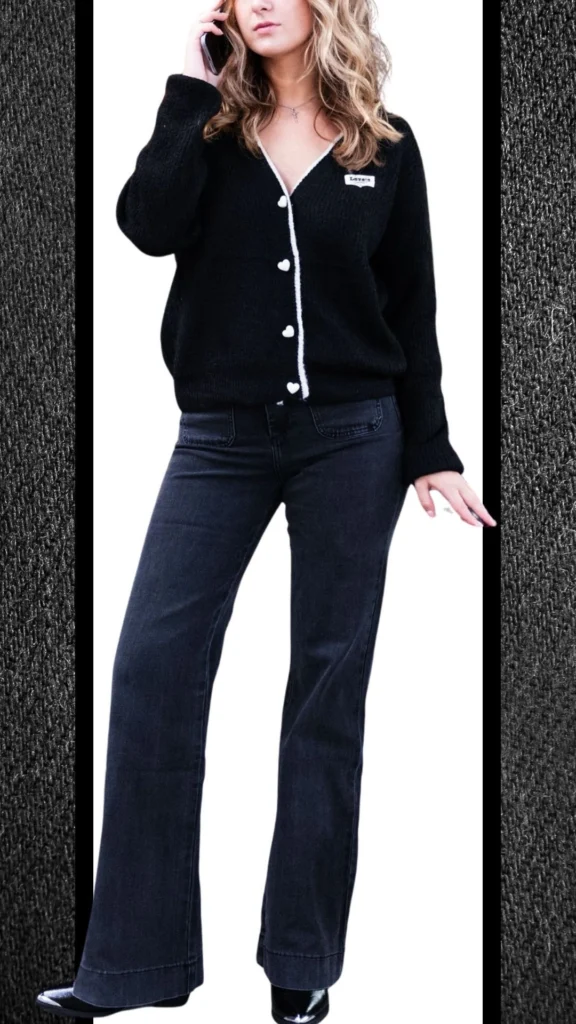 A stylish winter outfit featuring fitted black jeans with a soft, slightly textured finish and a black cardigan that has a cozy knit texture and contrasting heart-shaped buttons. The ensemble is completed with sleek black heeled boots that add a polished touch, enhancing the overall chic and warm look ideal for cooler months.
