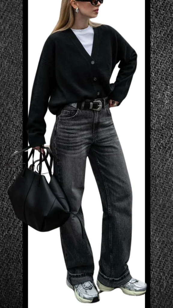 The outfit features high-waisted black jeans with a slightly faded texture, paired with a cozy oversized black cardigan that has a soft knit finish and a deep V-neckline. Complemented by a white t-shirt for contrast, the look includes a sleek black belt and a spacious black handbag, while the silver sneakers add a touch of modern flair. This ensemble is stylish and warm, perfect for winter's cooler months.