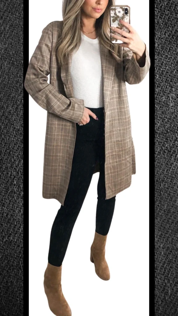 A stylish winter outfit features fitted black jeans paired with a cozy, ribbed white sweater and a long, plaid blazer in soft beige and brown tones. The look is complemented by taupe ankle boots, adding warmth and sophistication, while the textures create a balanced and chic aesthetic perfect for cooler months.