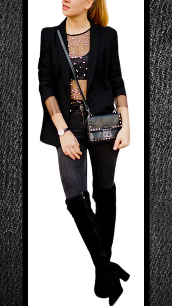 The outfit features high-waisted black jeans paired with a sheer, black long-sleeve top adorned with metallic embellishments, creating a striking textured contrast. A tailored black blazer enhances the look's sophistication, while knee-high black suede boots add warmth and elegance. The ensemble is completed with a chic black crossbody bag decorated with studs and a sleek watch, making it perfect for winter styling.