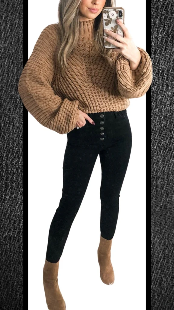 The outfit features a cozy, oversized tan knit sweater with textured ribbing, complemented by sleek, high-waisted black jeans featuring decorative button detailing. The combination is paired with chic, tan ankle boots, creating a warm yet stylish look perfect for winter. The rich contrast between the soft tan and deep black enhances the ensemble's sophistication while ensuring comfort for cooler months.