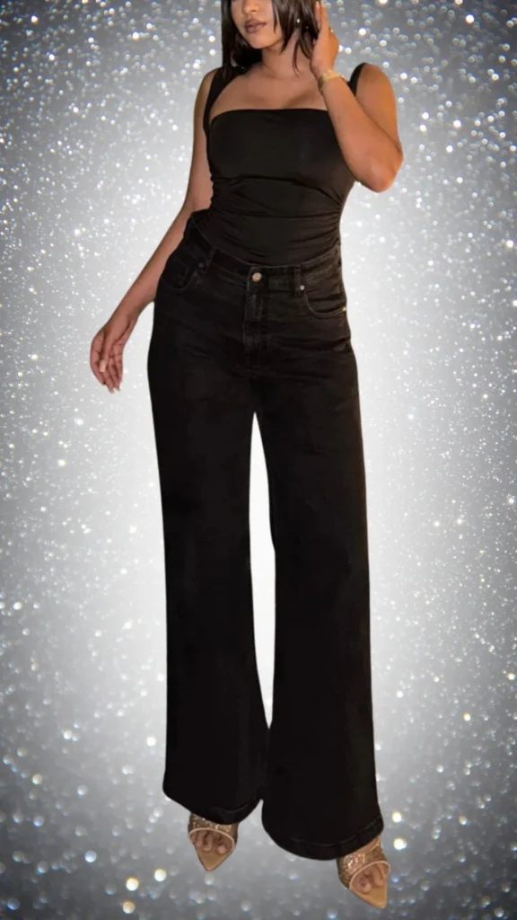 This chic all-black winter outfit features a fitted black tank top paired with high-waisted wide-leg black denim pants, creating a sleek silhouette. Complemented by elegant strappy heels, the look is polished and sophisticated, ideal for a stylish winter outing. The combination of soft textures and the classic black palette adds an effortless elegance to the ensemble.