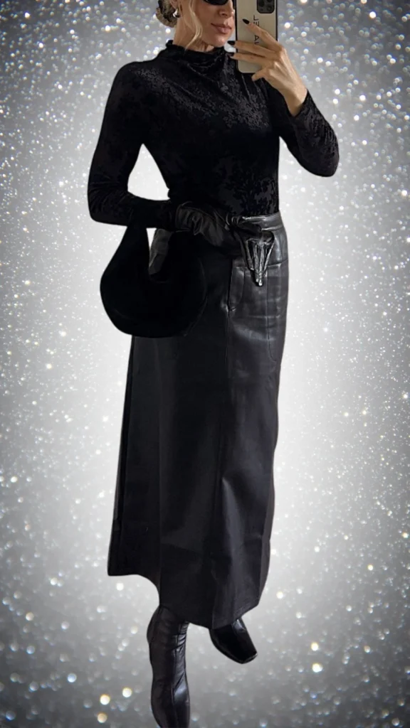 The outfit features a fitted black long-sleeve turtleneck made from a soft, textured fabric, complemented by a sleek, high-waisted leather skirt with a glossy finish. Accessories include matching leather gloves and stylish knee-high boots, creating a sophisticated and cohesive look perfect for winter elegance.