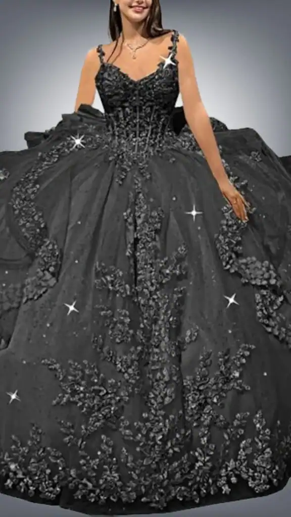 This stunning black quinceañera dress features a fitted corset bodice adorned with intricate floral appliqués and delicate beadwork, creating a shimmering effect. The voluminous skirt flows dramatically from the waist, embellished with additional floral details and playful stars throughout, giving it a whimsical yet elegant appearance. The overall design combines elegance with a sense of grandeur, perfect for a special celebration.