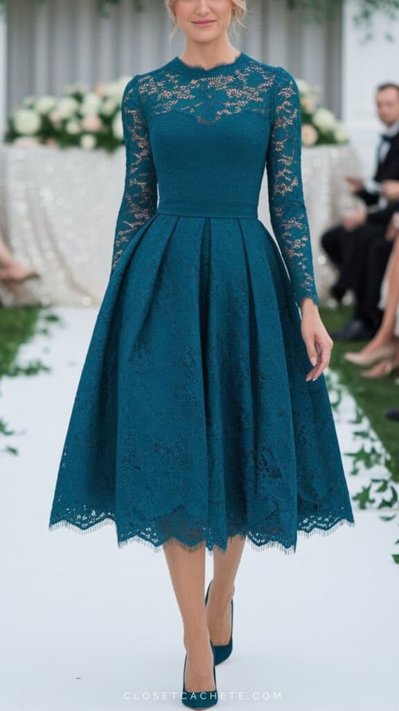 The elegant dress features a fitted bodice with intricate lace detailing and long sleeves, balancing sophistication with a touch of romance. The full, knee-length skirt adds grace and movement, while the rich teal color enhances the formal aesthetic, perfectly suited for a black tie optional event. Paired with matching high heels, this ensemble achieves a polished yet approachable look.