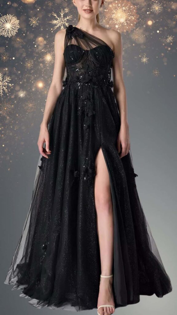 A black winter formal dress features a one-shoulder design with a soft tulle overlay and floral embellishments that add texture and elegance. The dress has a fitted bodice, a flowing skirt with a thigh-high slit, and subtle sparkles that enhance its sophisticated look, making it perfect for formal occasions.
