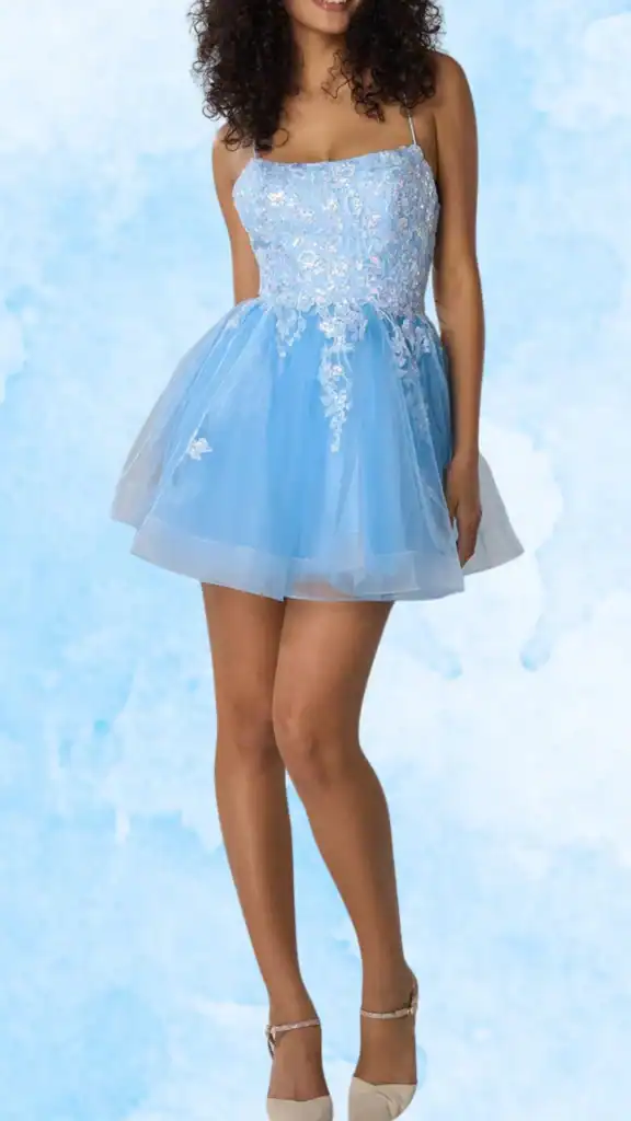 A young woman wearing a strapless, light blue homecoming dress with delicate floral embroidery on the bodice and a flared tulle skirt. The dress has thin spaghetti straps and a princess-like silhouette, paired with nude heels. The background is a soft watercolor-style light blue.
