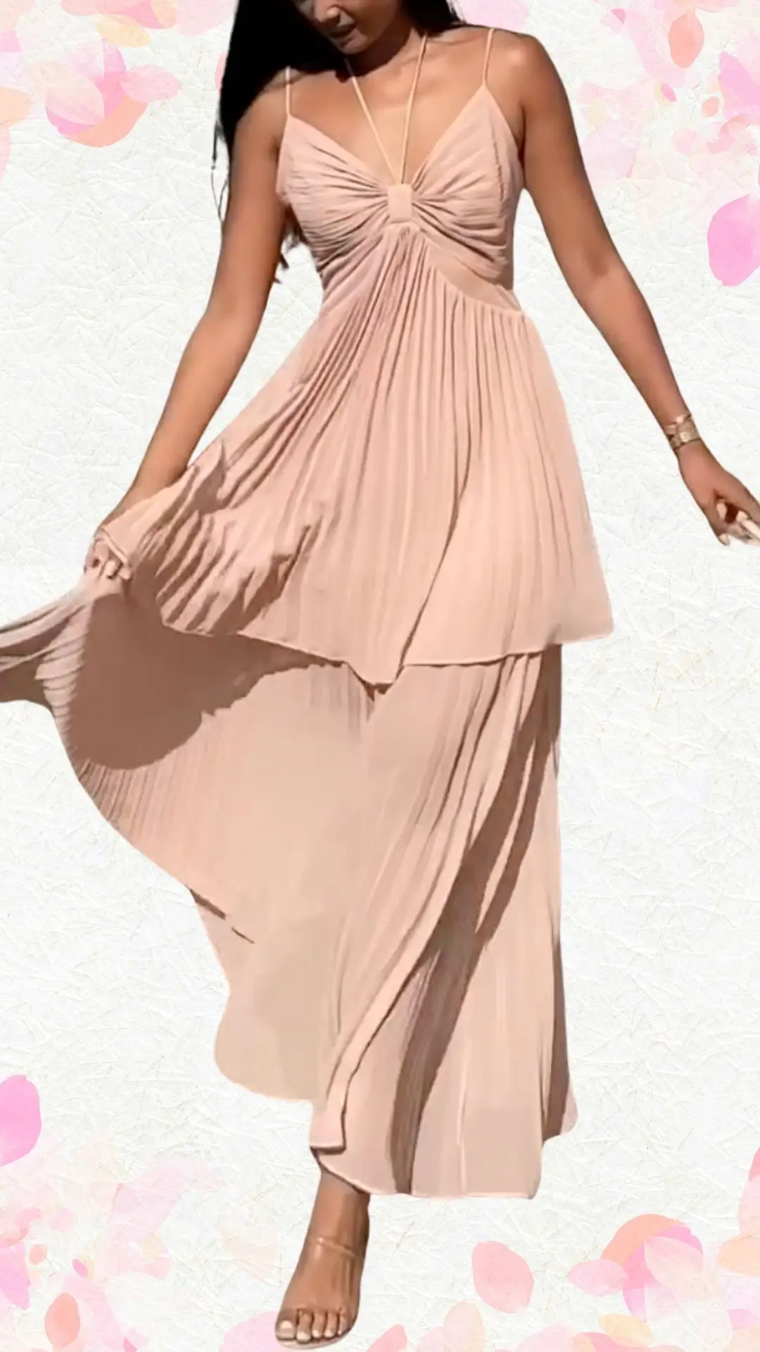 A flowing, blush pink maxi dress features delicate spaghetti straps and a pleated bodice that gathers elegantly at the center, creating a whimsical yet polished silhouette. The fabric is lightweight and airy, enhancing the dress’s playful movement, while a layered hem adds a touch of sophistication, perfect for a celebratory occasion. Subtle details like the soft draping and gentle playfulness make it appropriate for a bridal shower without being overly formal.