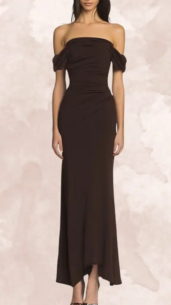 The dress is a rich chocolate brown, floor-length bridesmaid gown featuring an off-the-shoulder neckline and elegant puffed sleeves. Its fitted silhouette is accentuated by gathered detailing at the waist, creating a flattering shape, while the hemline has a subtle dip at the front for a modern twist. The smooth fabric adds a sleek finish, enhancing the dress's sophisticated appeal.