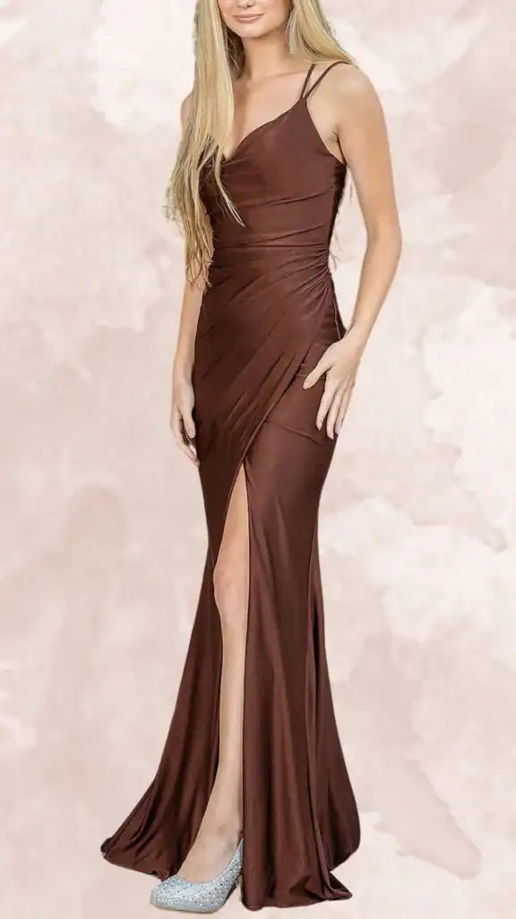 The dress is a sleek, chocolate brown, floor-length gown featuring a fitted silhouette with a deep V-neckline and delicate spaghetti straps. It is designed with a ruched waist and a thigh-high side slit, adding drama and elegance to the overall look. The fabric has a smooth, glossy finish, enhancing its luxurious appearance, making it a stylish choice for bridesmaids.