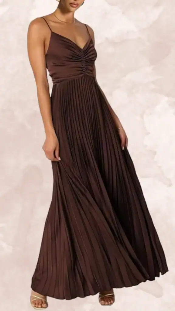The brown bridesmaid dress features a flattering V-neckline with delicate spaghetti straps and a gathered bodice, enhancing the silhouette. The floor-length design is characterized by flowing, pleated fabric that creates an elegant movement. Its rich chocolate shade exudes sophistication, making it an ideal choice for formal occasions.