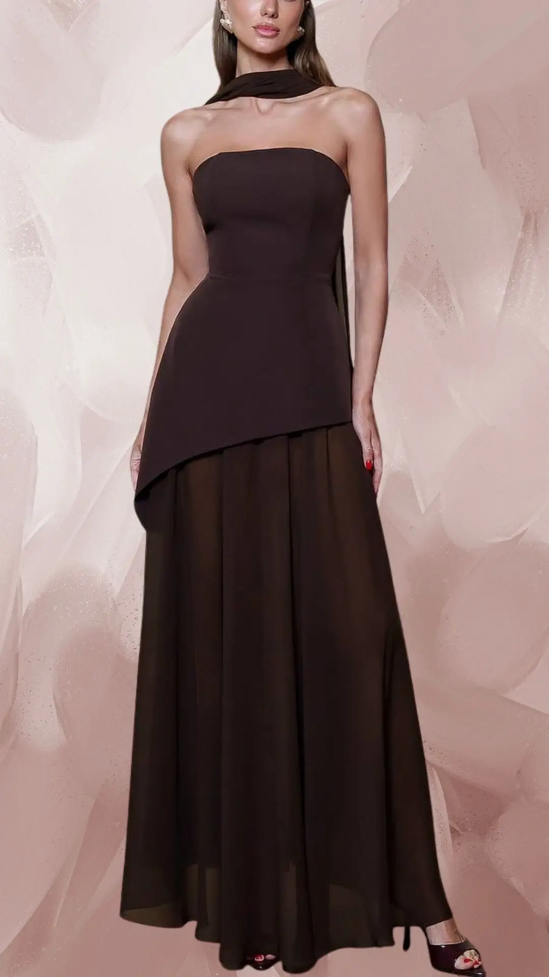 This elegant brown dress features a strapless bodice with a flowing, floor-length skirt crafted from lightweight chiffon. The dress has a layered design with a slightly asymmetrical hem and is paired with stylish open-toe heels, enhancing its contemporary appeal. The deep, rich shade of brown adds sophistication to this striking outfit.