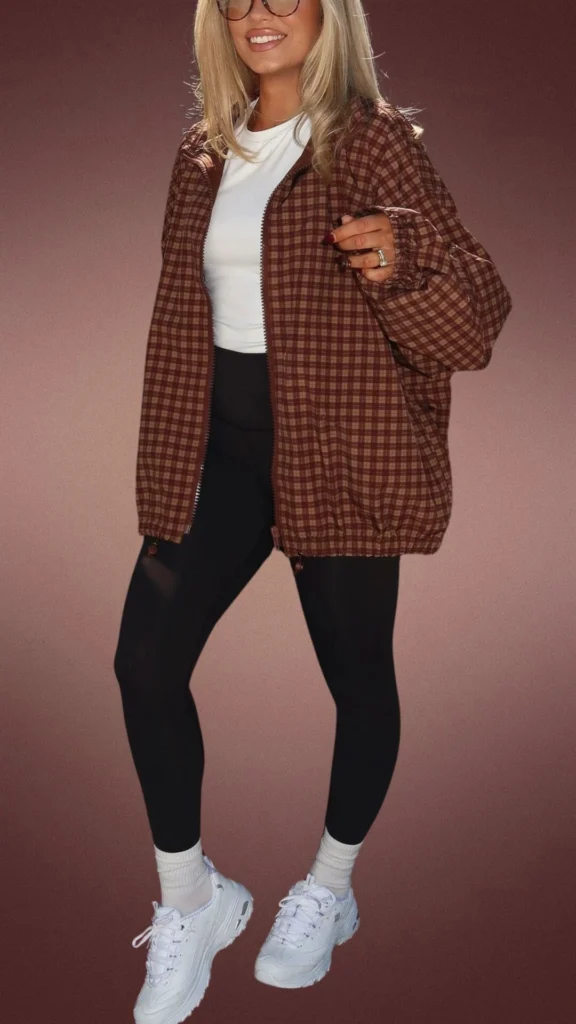 The outfit features cozy brown plaid leggings paired with a relaxed-fit white t-shirt, layered under a loose-fitting brown checkered jacket made from a soft, textured fabric. Complementing the look are chunky white sneakers and ankle-length socks, creating a warm, comfortable style ideal for winter's cooler months.