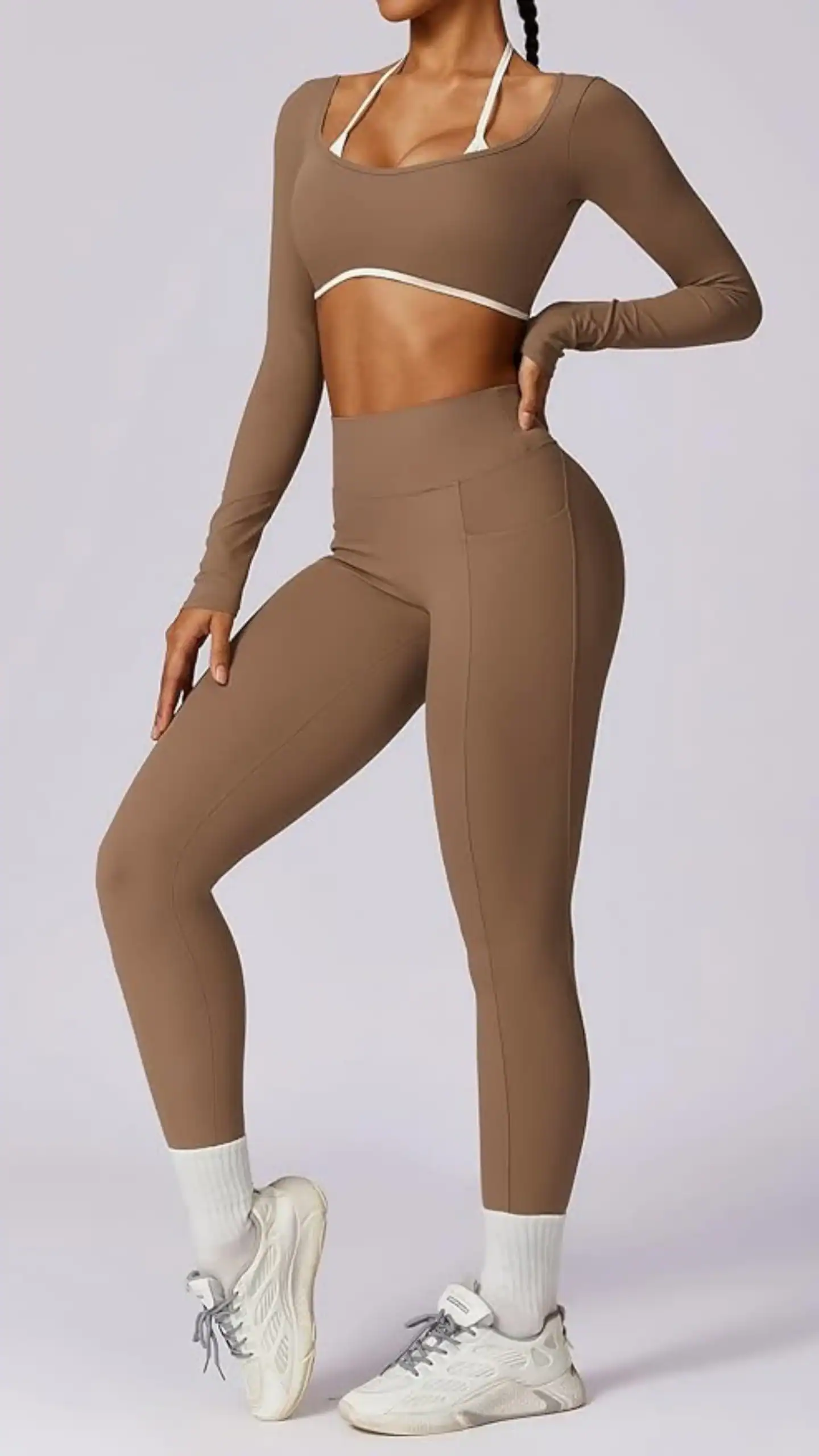 This two-piece women's workout set features a rich, earthy brown tone with a soft, buttery texture made from 78% Polyamide and 22% Elastane, allowing for flexibility and comfort during exercise. The high-waisted leggings include a scrunch design for added style and pockets for convenience, while the long-sleeve crop top offers light-to-medium support with a trendy sweetheart neck and built-in bra, perfect for yoga or casual workouts.