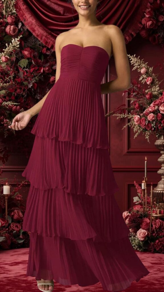 Strapless burgundy bridesmaid dress featuring a fitted bodice with subtle pleating and a flowing, tiered skirt. The lightweight fabric creates an elegant drape, accentuated by soft pleats on each layer, providing movement and grace. This dress combines sophistication and romantic charm, making it a perfect choice for a wedding.