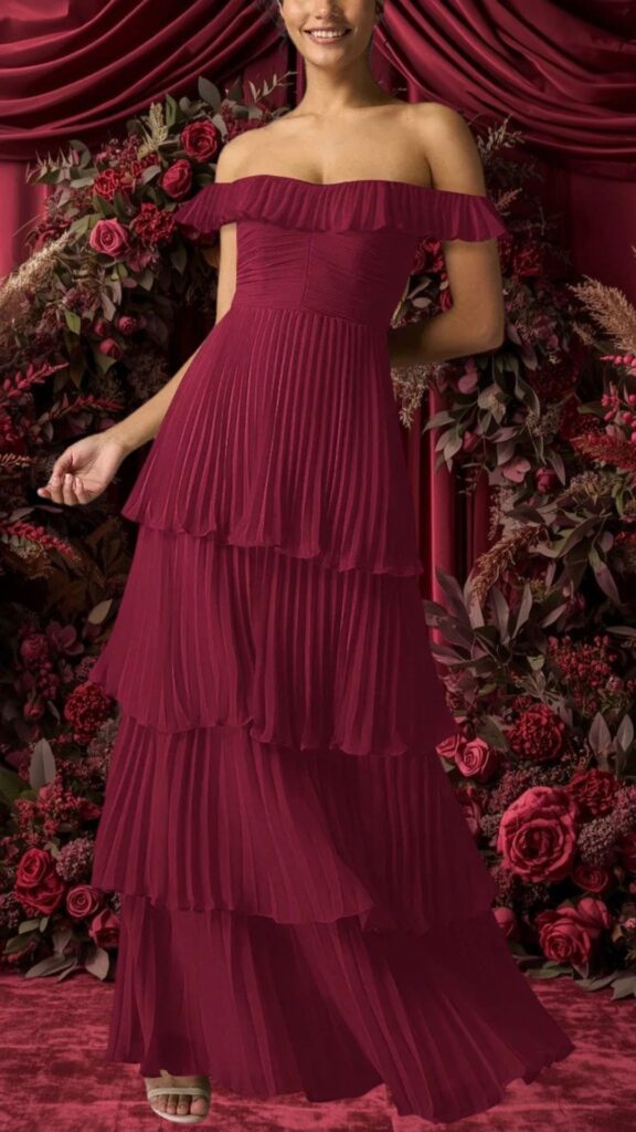 A strapless burgundy bridesmaid dress features a pleated design with a ruffled neckline and a tiered, flowy silhouette. The dress has a fitted bodice that transitions into cascading layers, offering an elegant and romantic look suitable for weddings. Its rich color and textured fabric add depth and sophistication, making it perfect for bridesmaids.