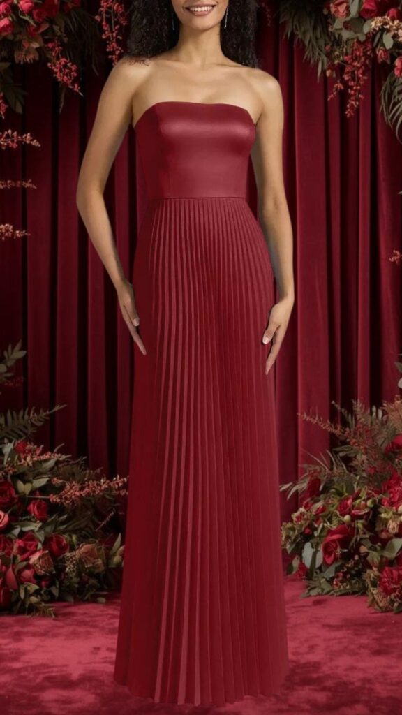 The dress features a strapless, fitted bodice that transitions into a flowing pleated skirt, all in a deep burgundy hue. The smooth satin texture enhances the elegant silhouette, while the structured pleats add movement and visual interest. This gown is perfect for bridesmaids, offering a blend of sophistication and comfort for special occasions.