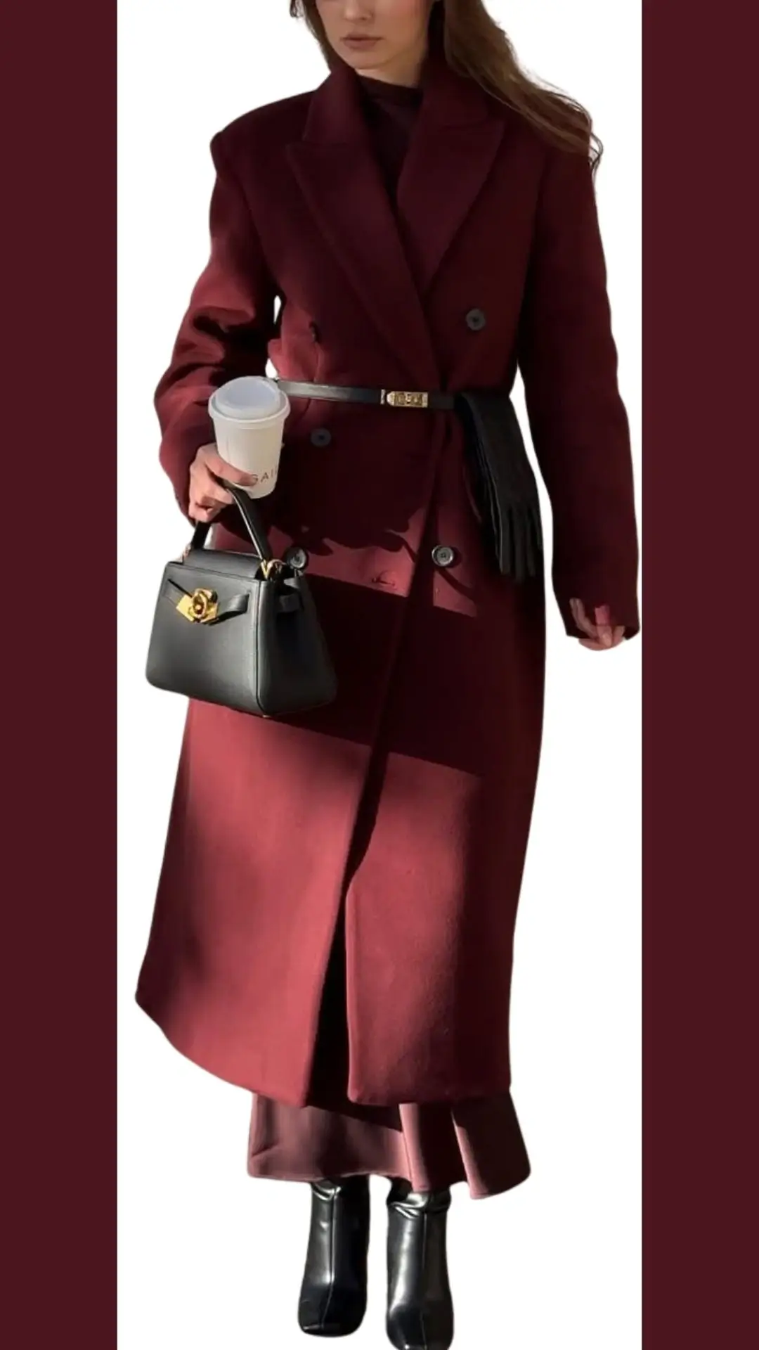 The outfit features a long, tailored burgundy coat made from a structured, warm fabric. It has a double-breasted design with sleek lapels, and the wearer accessorizes with a fitted black belt that cinches the waist, complemented by high-shine black ankle boots and a chic black handbag with a decorative gold clasp. A soft, burgundy underlayer peeks out, adding depth to the ensemble.