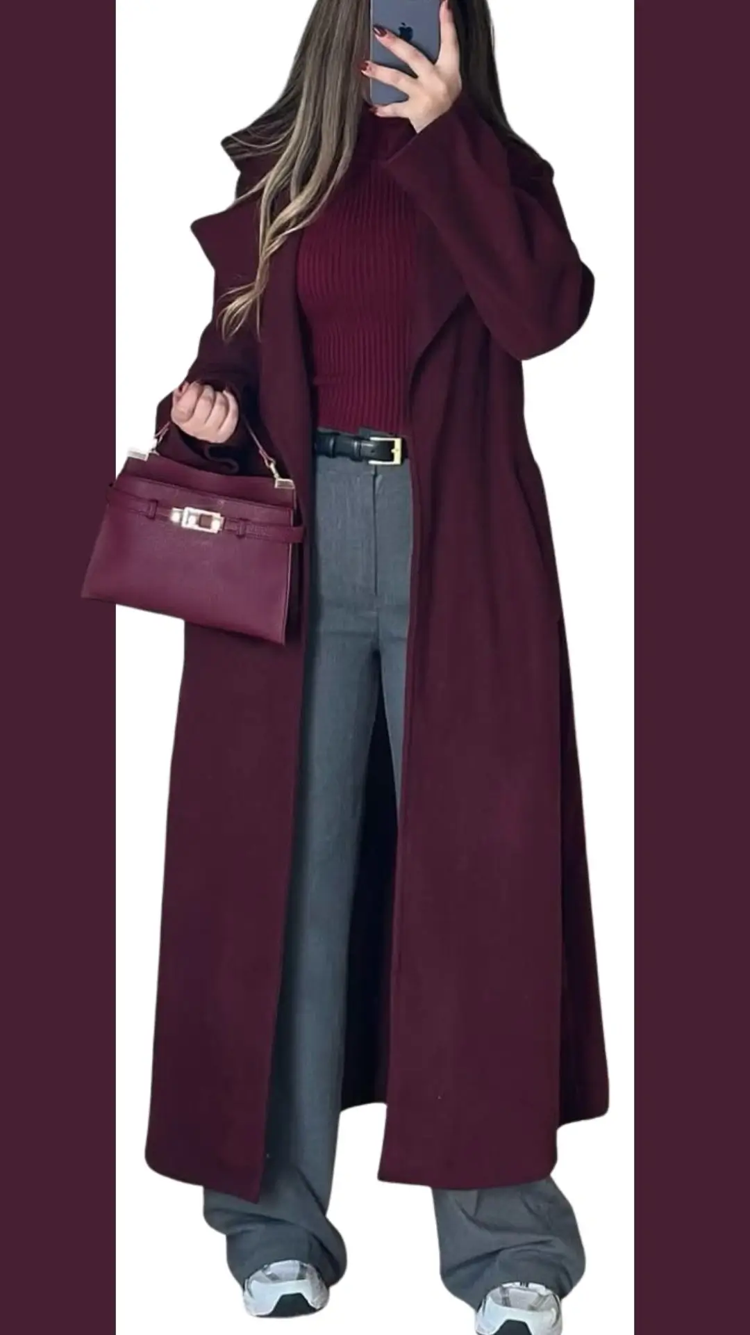 A long, open-front burgundy coat features a relaxed silhouette with wide lapels, layered over a matching ribbed burgundy sweater. Paired with high-waisted gray trousers and adorned with a sleek burgundy handbag, the outfit is completed with sporty white and gray sneakers, offering a stylish blend of elegance and casual comfort.
