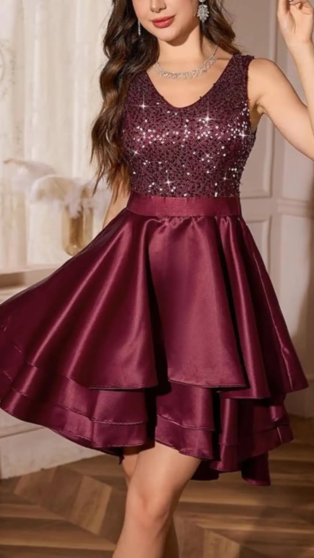 This homecoming dress features a rich burgundy color with a shimmering sequin bodice and a layered satin skirt, providing a flattering fit that accentuates the waist and creates playful volume. The overall vibe is trendy and youthful, making it perfect for a festive teenage occasion like homecoming or a school dance.