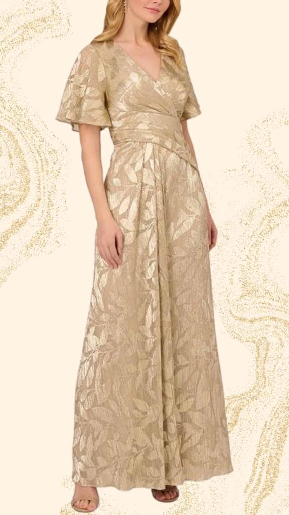 Long champagne-colored mother of the bride dress featuring a wrap-style V-neckline and elegant flutter sleeves. The gown has a flowing silhouette with intricate leaf-patterned textures, creating a sophisticated and polished look perfect for a wedding. The fabric drapes gracefully to the floor, enhancing its classy appeal.