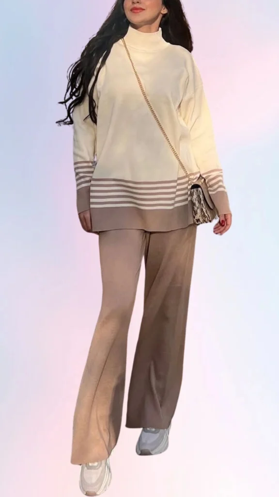 The outfit features a cozy ivory sweater with a high neckline and soft, relaxed fit, complemented by light brown, flowy wide-leg pants that enhance comfort. Subtle striped detailing on the sweater adds visual interest, while the ensemble is completed with casual sneakers, creating a chic yet laid-back look perfect for easygoing days. The overall color palette of soft neutrals promotes a calm, effortless aesthetic.