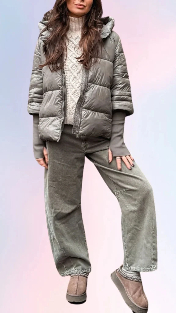 A puffy, slate-grey puffer jacket layered over a cozy, cream-colored knitted sweater features a textured cable pattern, while wide-legged, light grey corduroy pants introduce a relaxed fit. Completing the look, soft, taupe slip-on shoes offer comfort and ease, making this outfit perfect for a laid-back, stylish day.