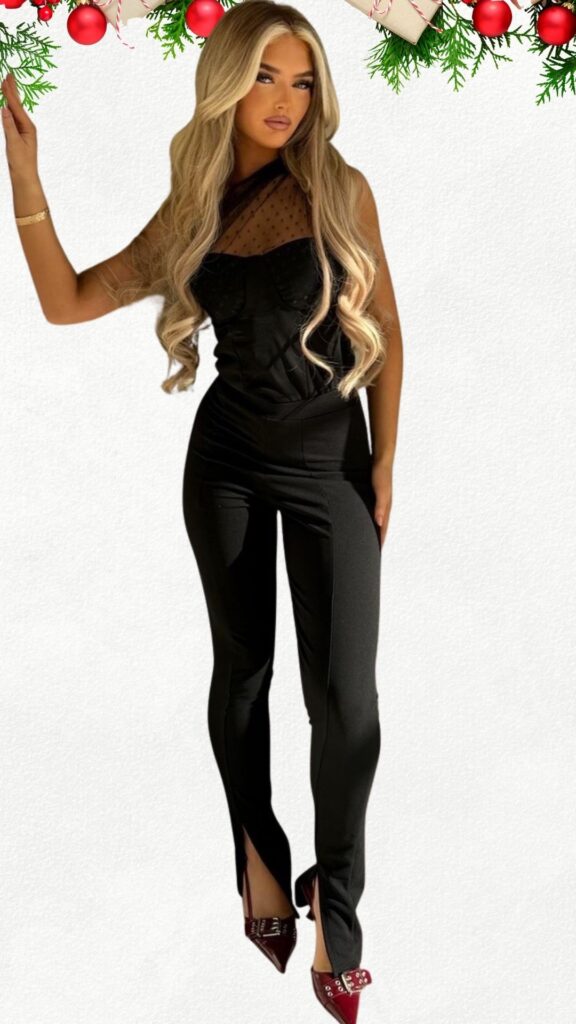 The outfit features a sleek black jumpsuit with a fitted silhouette and sheer, dotted tulle detailing along the bodice, creating an elegant contrast. This ensemble is paired with striking burgundy pointed-toe heels adorned with silver embellishments, adding a chic touch to the overall look. The combination of textures and colors highlights a sophisticated yet festive style perfect for a dressy Christmas occasion.