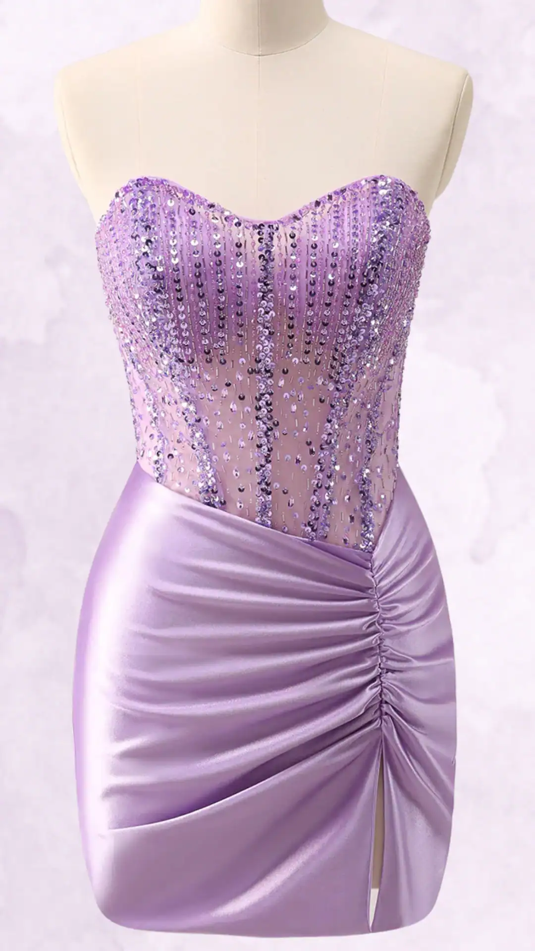 This dazzling homecoming dress features a fitted strapless bodice adorned with shimmering purple sequins, transitioning into a smooth, satin mini skirt with gathered detailing and a side slit. The overall vibe is chic and playful, ideal for a youthful, trendy occasion such as a school dance or party.