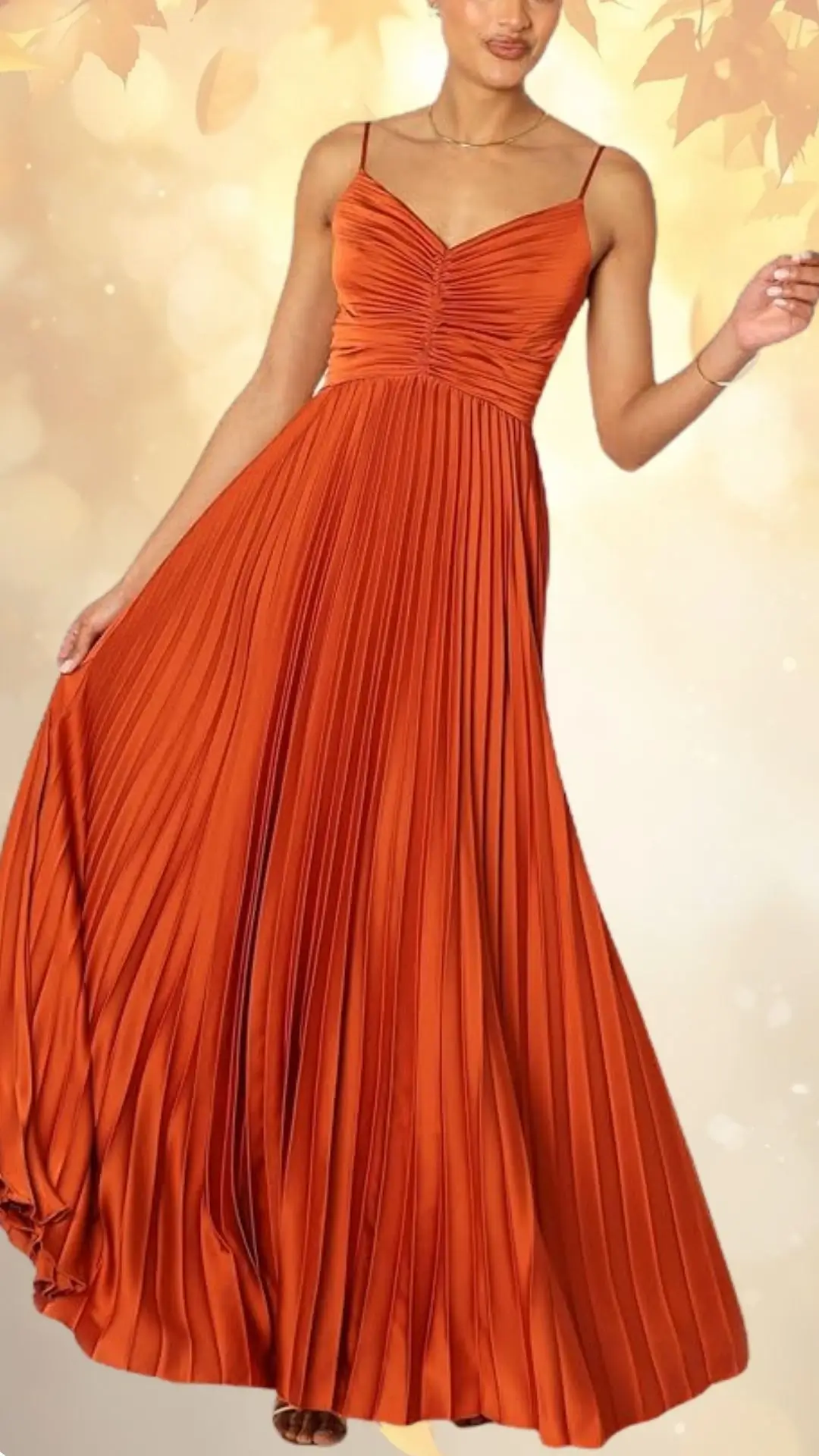 A fall bronze wedding guest dress featuring earthy, warm tones with a fitted bodice and thin straps. The dress has a flowing, pleated skirt that cascades gracefully to the floor, creating an elegant silhouette. Its rich color and texture enhance its suitability for autumn celebrations.