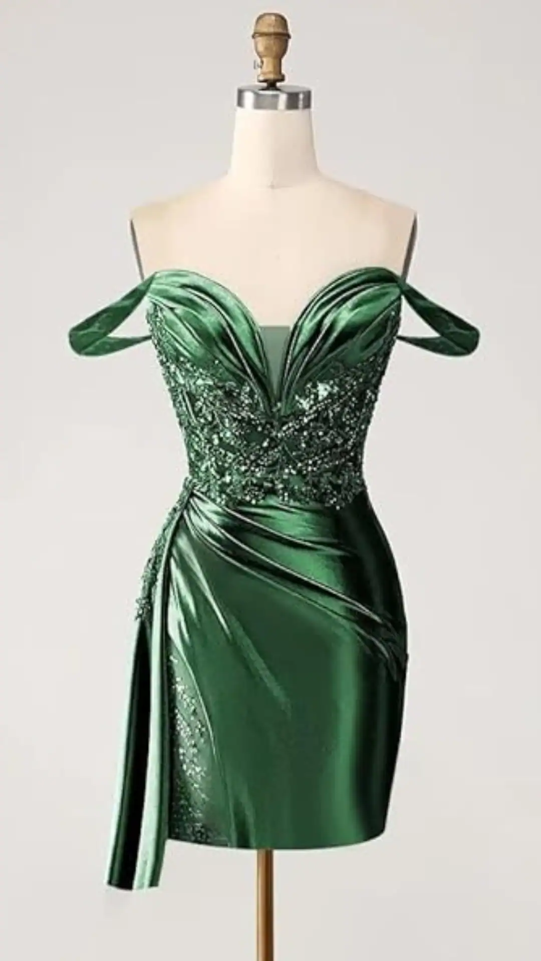 This elegant homecoming dress features a fitted silhouette in rich emerald green satin, adorned with intricate beading and delicate draping for added texture. The off-the-shoulder design and sweetheart neckline create a bold yet romantic aesthetic, making it perfect for teens attending formal events like prom or school dances.