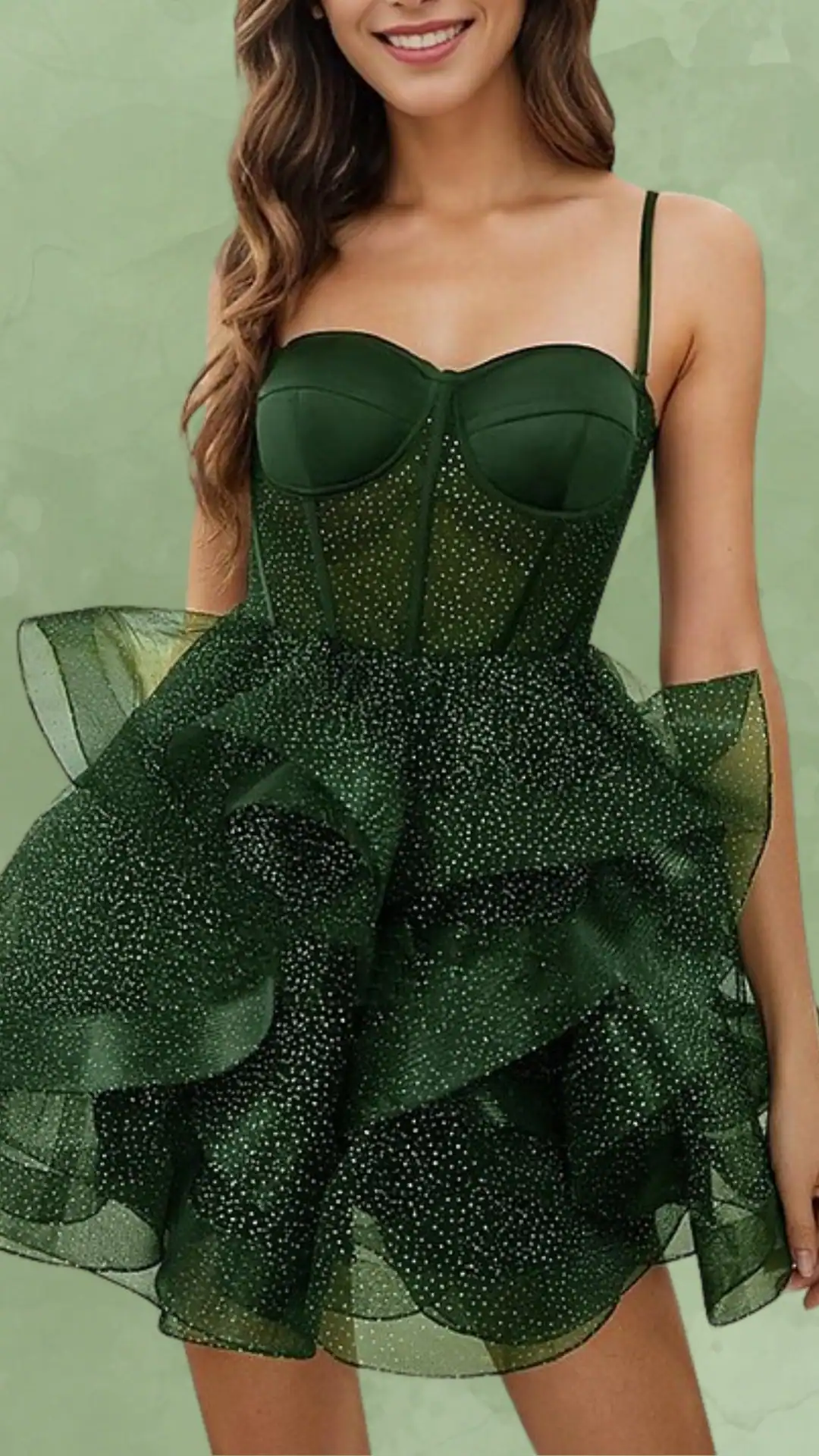 This emerald green homecoming dress features a fitted, corsetted bodice with delicate spaghetti straps and an enchanting layered skirt embellished with tiny glittering accents, creating a playful volume. Its youthful and trendy vibe makes it an ideal choice for a school dance or formal event, perfect for teenage girls looking for a touch of glamor.