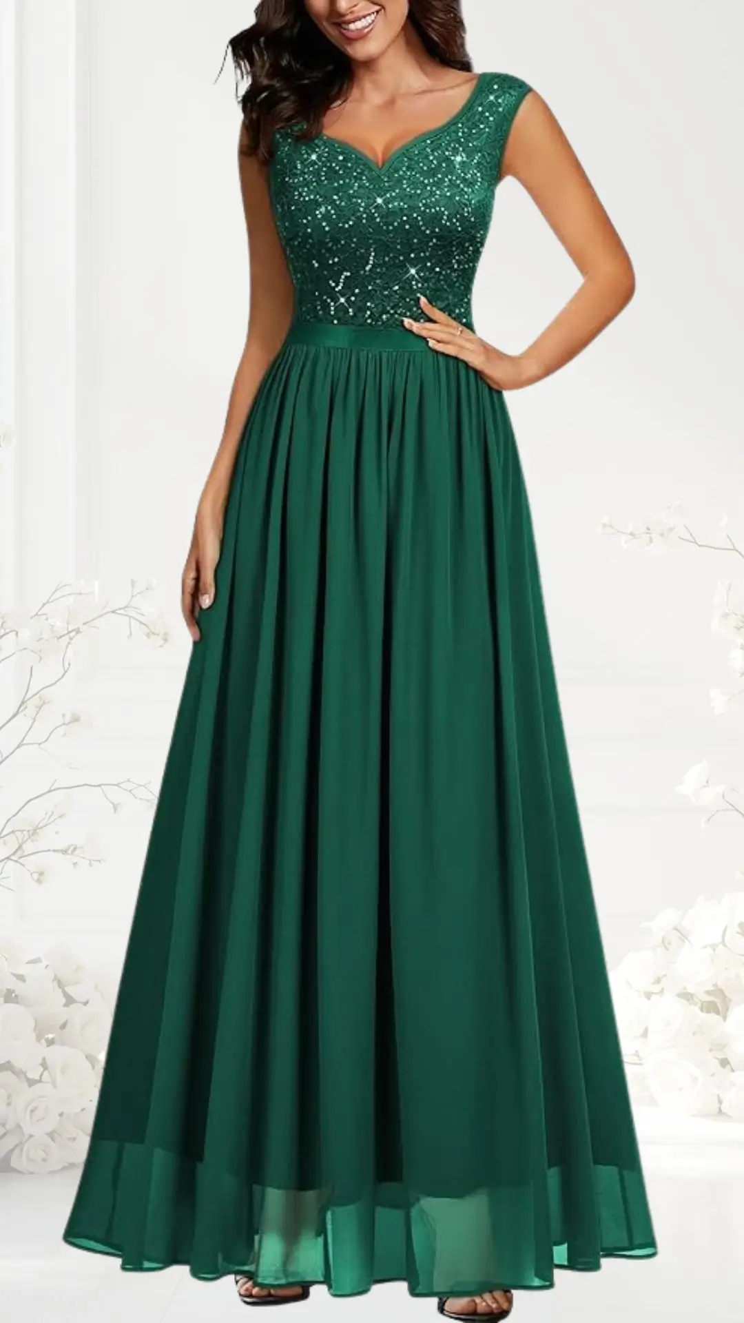 The dress features a fitted, sequined emerald green bodice with a flattering V-neckline and sleeveless design. The flowy A-line skirt extends to the floor, made from lightweight fabric that adds movement and elegance. The outfit is styled to enhance the wearer's silhouette, perfect for formal occasions.