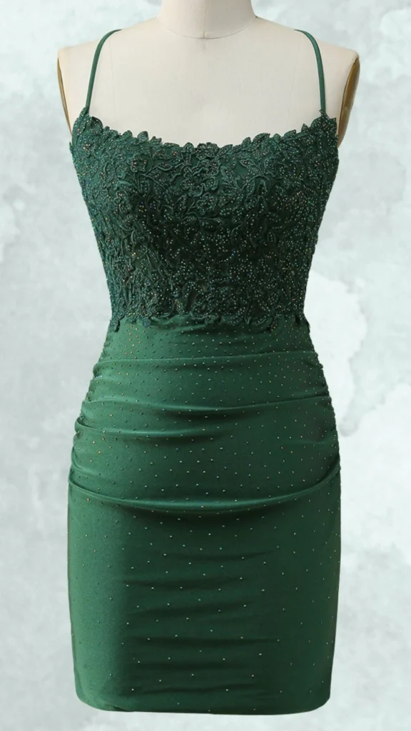 The dress features a fitted silhouette in a deep emerald green, adorned with intricate floral lace detailing at the bodice embellished with shimmering beads. It has thin spaghetti straps and a sleek, ruched mini skirt that hugs the body for a flattering fit, accentuating curves while maintaining an elegant allure. The overall design combines sophistication with a touch of sparkle, making it perfect for homecoming celebrations.