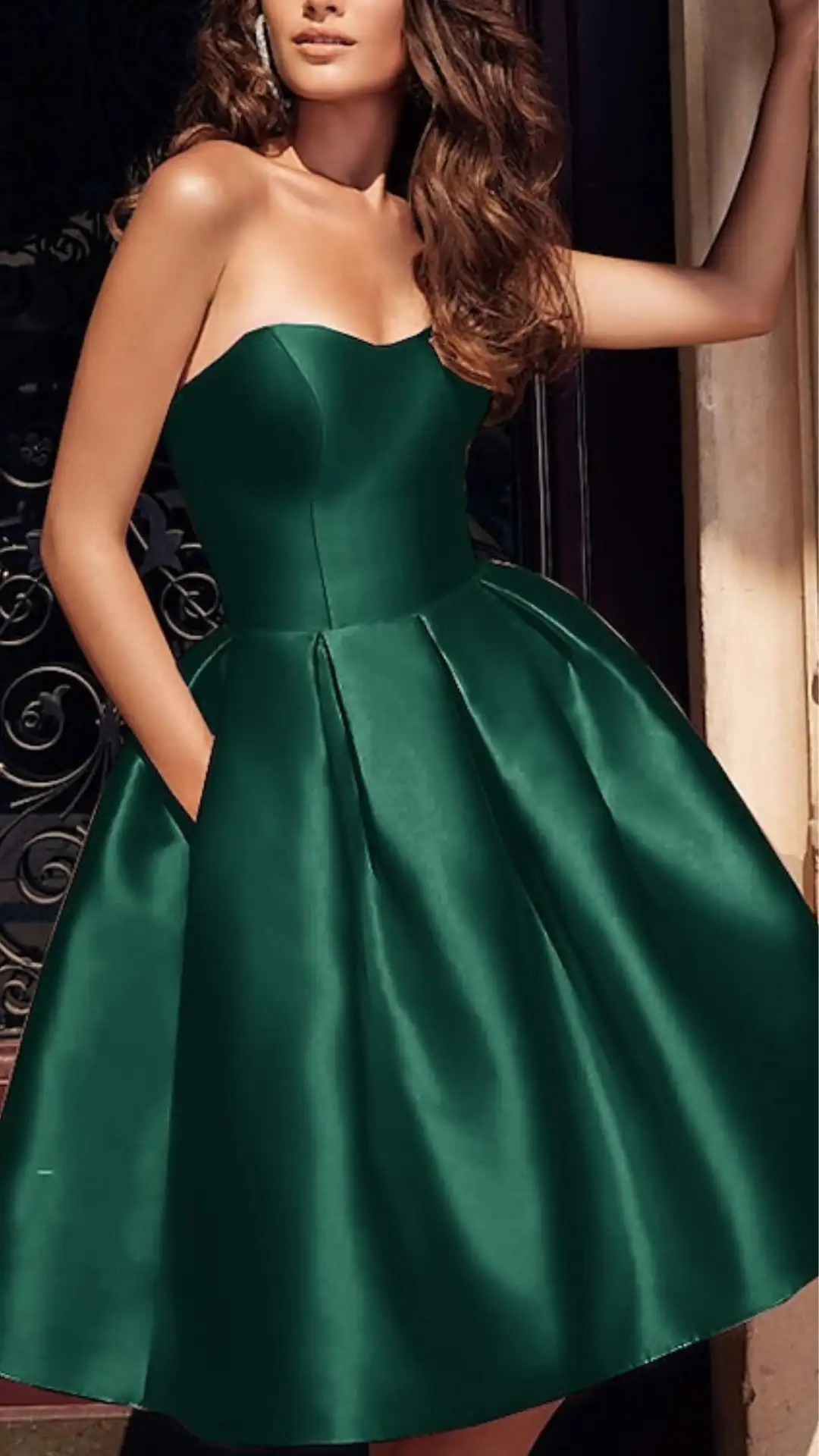 The dress features a classic strapless design with a fitted bodice and a voluminous, knee-length skirt made from smooth, satin fabric that has a slight sheen, presenting a rich emerald green color. Its elegant silhouette and timeless style make it perfect for homecoming events, appealing to teenage girls seeking a chic and sophisticated look.