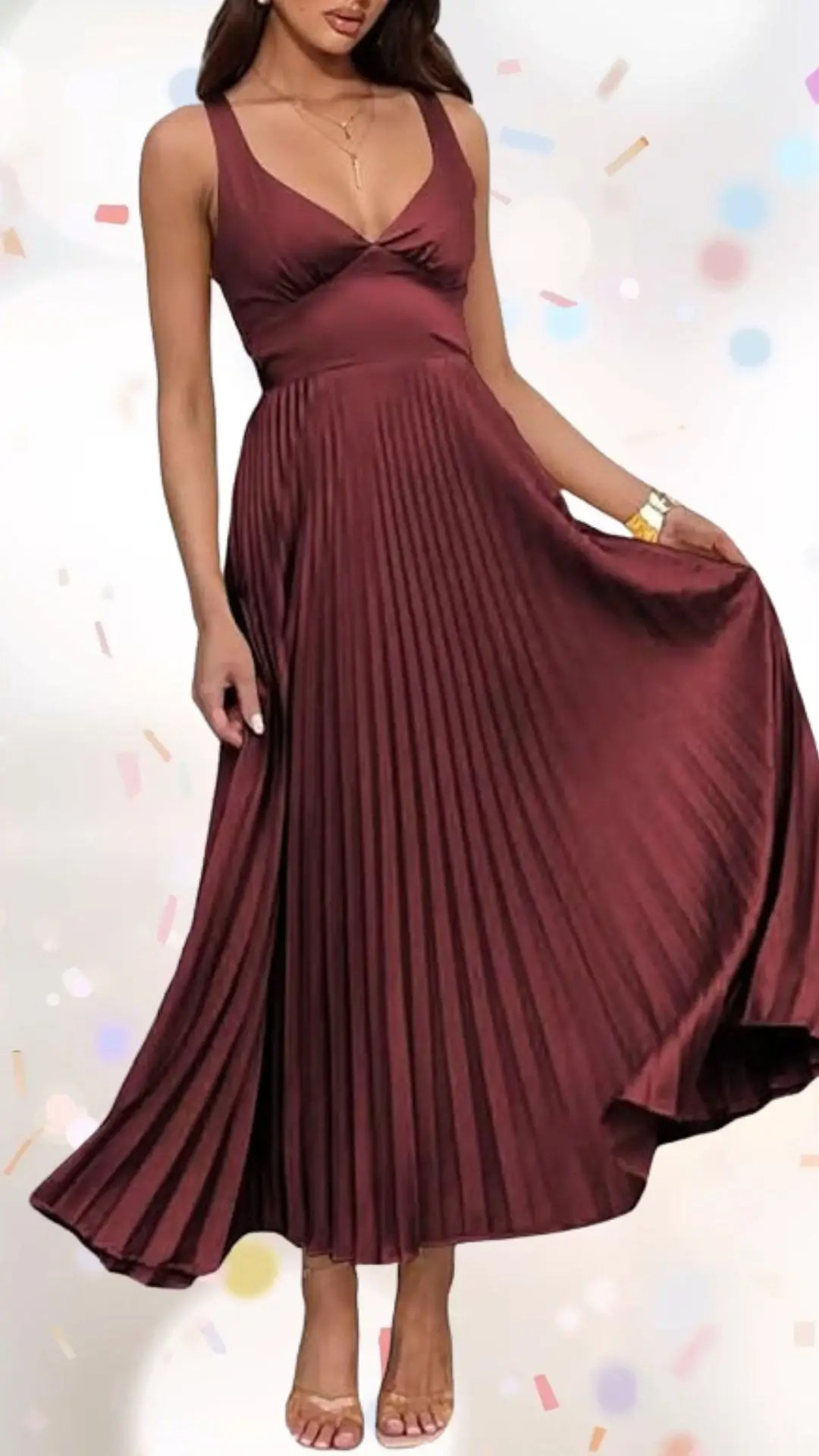 The dress features a rich burgundy color in a flowing, pleated design that elegantly sways with movement. It has a deep V-neckline and wide straps, adding a touch of sophistication while maintaining a playful feel, perfect for a celebratory occasion. The smooth fabric drapes beautifully, balancing class and whimsy without being overly formal or casual.
