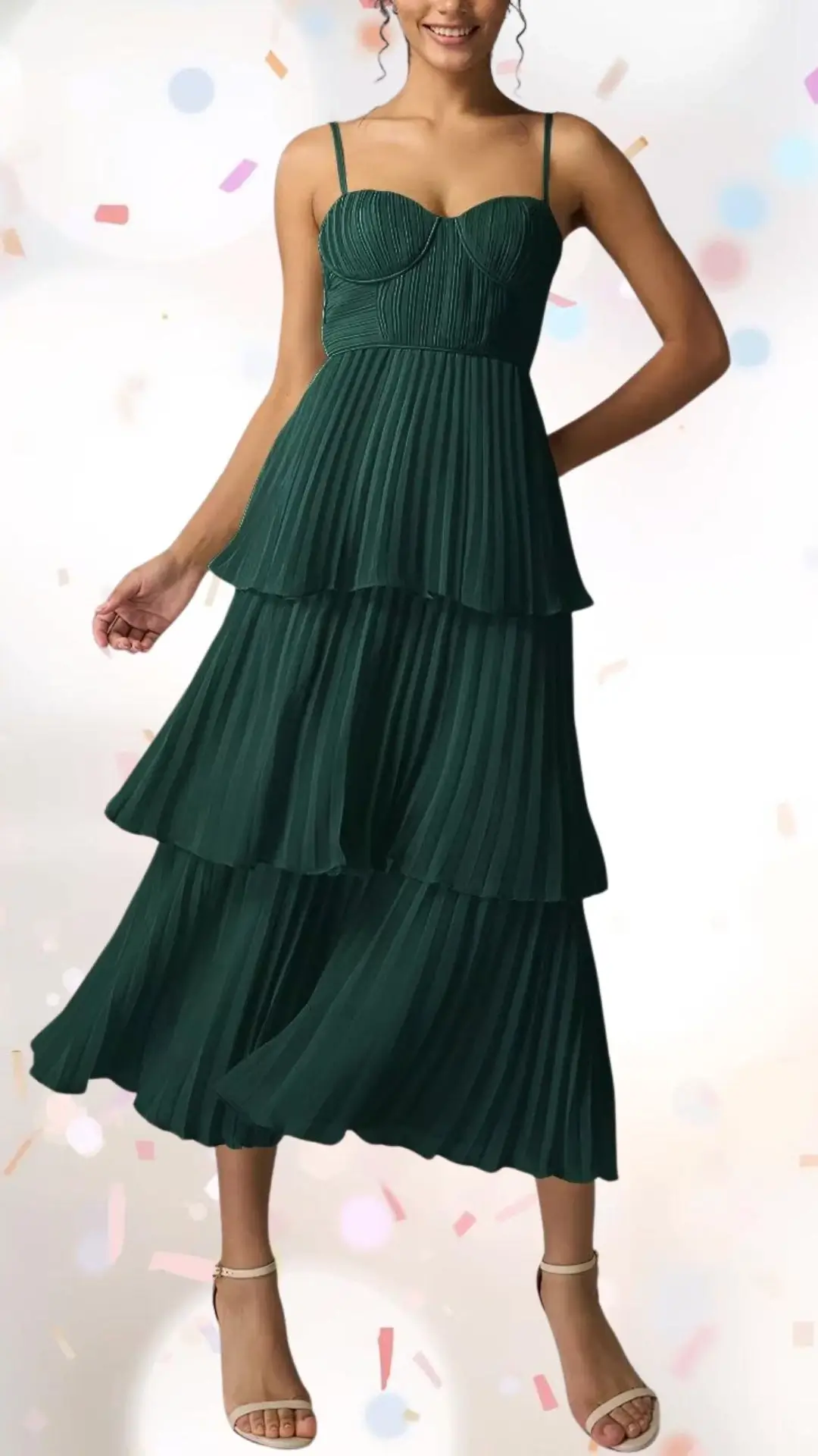 A tiered midi dress in rich emerald green features light, flowing pleats that create a sense of movement. The sweetheart neckline and delicate spaghetti straps add a touch of elegance, while the playful tiers lend a whimsical charm, making it suitable for celebrations without being overly formal. The look is completed with delicate strappy sandals that enhance the outfit's festive spirit.