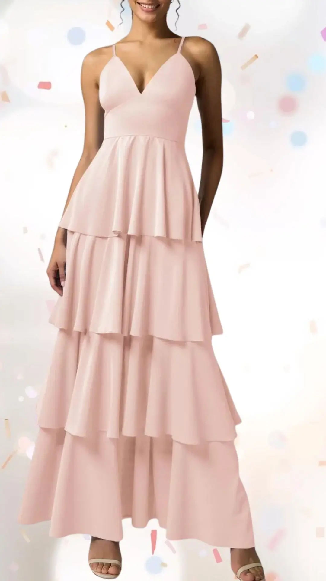 The dress features a playful, tiered design in soft pink fabric, exuding an elevated yet whimsical charm. It has delicate spaghetti straps, a flattering V-neckline, and flowing layers that create movement, making it perfect for a festive engagement party. The lightweight material adds a touch of ease, balancing sophistication with a fun celebratory vibe.