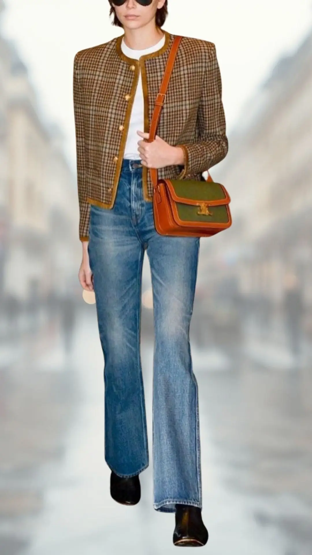 A model wears a tailored brown checkered cropped jacket with a round neckline and gold buttons over a fitted white T-shirt. Paired with high-waisted flare jeans in a light wash and black ankle boots, the outfit is completed with a stylish two-tone green and brown handbag and oversized sunglasses, exuding a chic, casual vibe.
