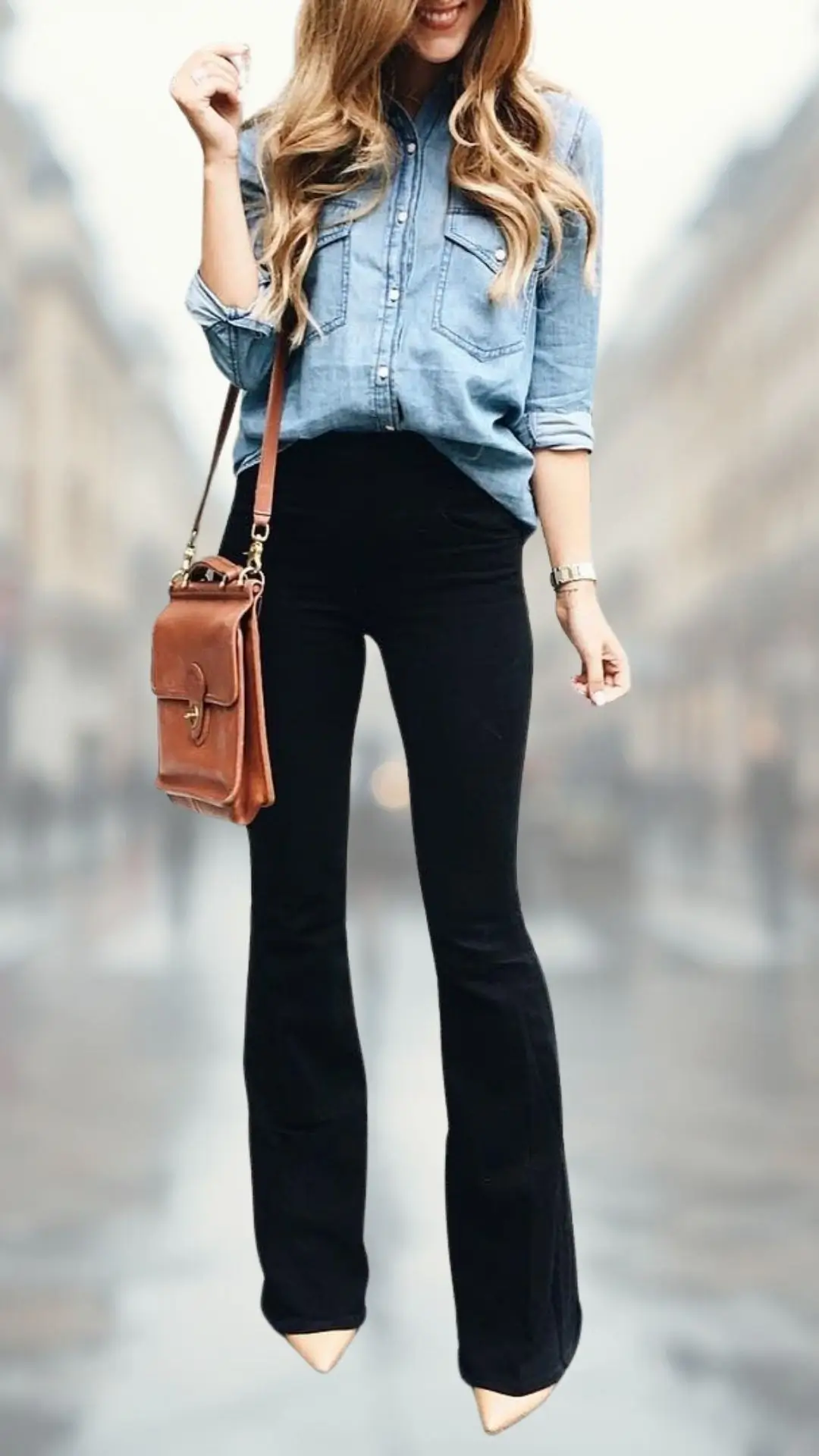 A stylish outfit features a light blue denim button-up shirt with a relaxed fit and long sleeves, paired with high-waisted black flare jeans that accentuate the legs. The ensemble is completed with nude pointed-toe heels and a brown crossbody bag, adding a chic touch to the look. The combination of textures and colors creates a visually appealing contrast while maintaining an effortless vibe.