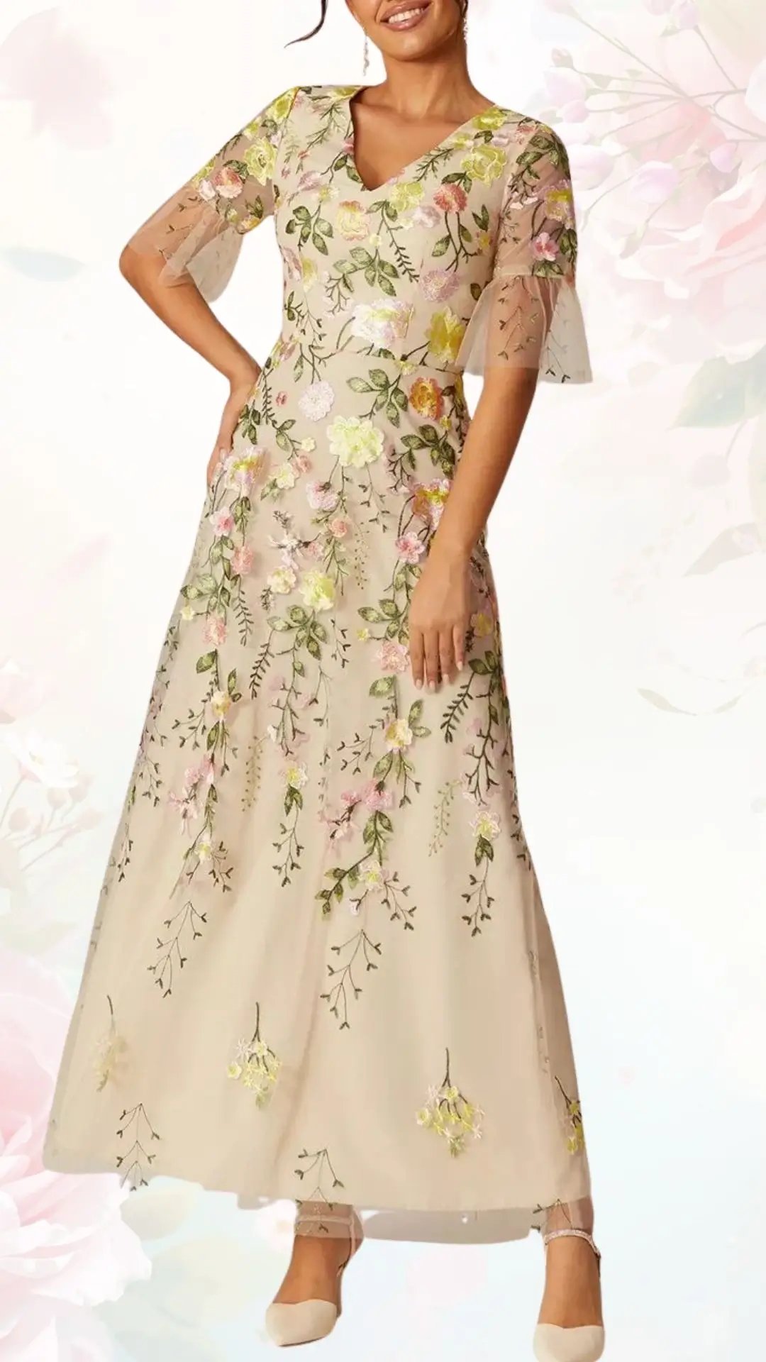 A floral spring wedding guest dress features a soft beige background adorned with colorful embroidered flowers in pink, yellow, and green. The dress has a flattering V-neckline and elegant, sheer short sleeves, flowing gracefully to the floor, enhancing its romantic appeal. The overall design is light and airy, perfect for a spring celebration.
