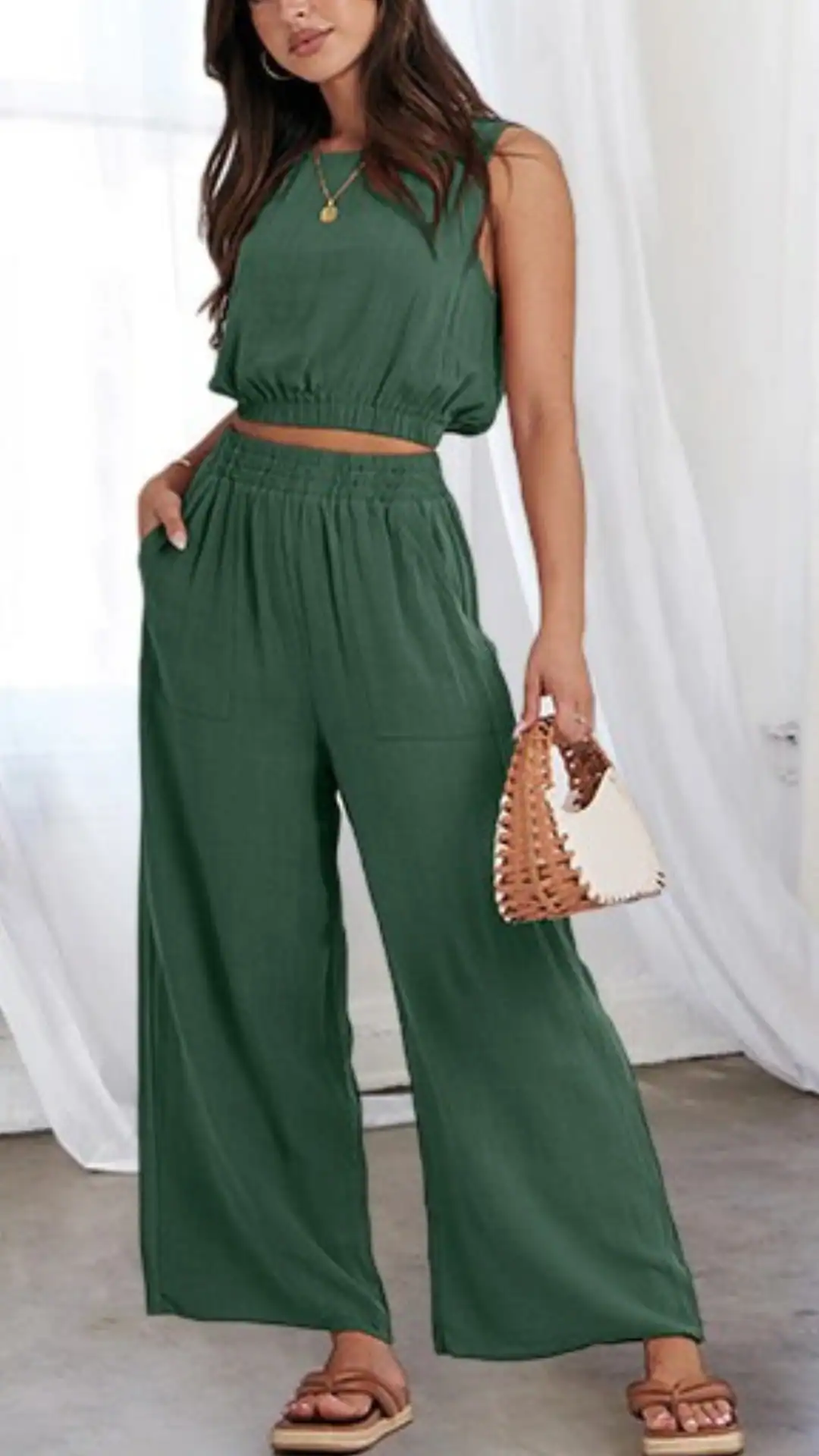 The outfit features a lightweight, textured linen matching set in a rich forest green, consisting of a cropped sleeveless top and wide-leg pants with an elastic waistband and side pockets. Ideal for casual outings, this relaxed yet chic ensemble exudes a laid-back, bohemian vibe.